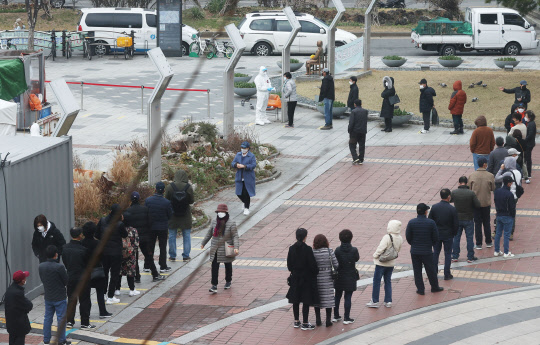 코로나19 신규 확진자가 닷새 연속 400명대를 기록한 21일 오전 서울 구로역광장에 마련된 임시 선별진료소 앞에 시민들과 외국인들이 검체 검사를 받기 위해 줄을 서 있다.   연합뉴스